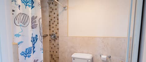 A bathroom with a shower, toilet, and tiled floor.