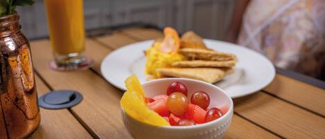 Een ontbijttafel met een fruitschaal, toast en een glas sinaasappelsap.