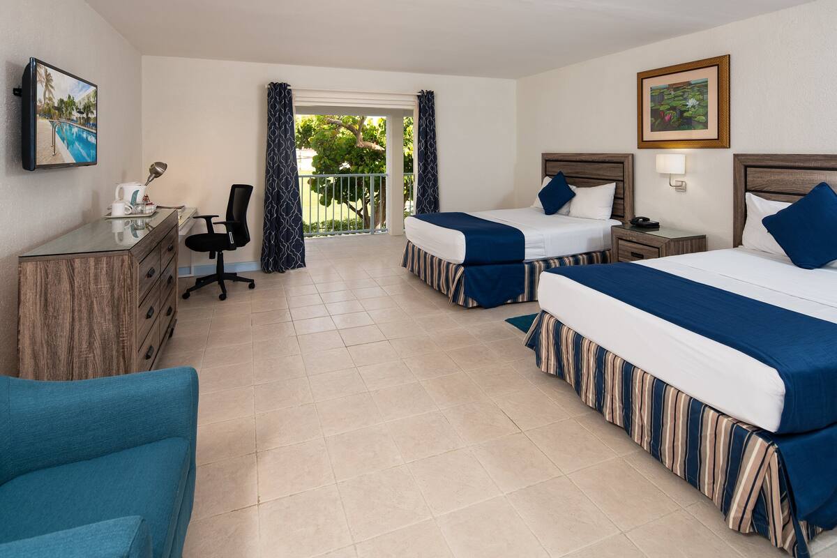 A hotel room with two beds, a desk, a chair, and a view of a pool.