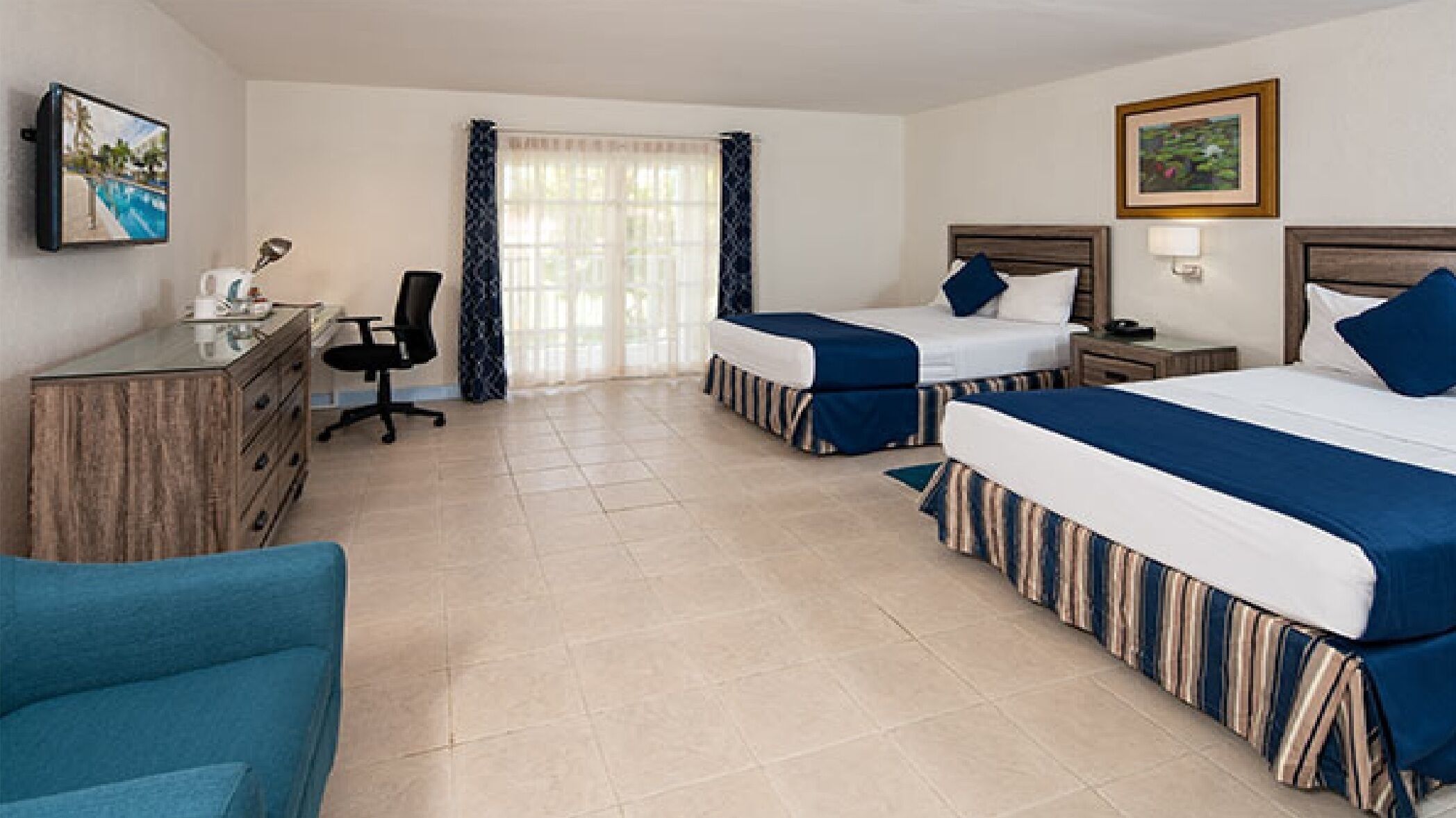 A hotel room with two beds, a desk, a chair, and a TV.