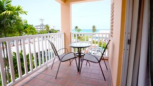 A balcony with a table and chairs, a view of the ocean, and a white railing. - Worthing Court Apartment Hotel (Worthing)