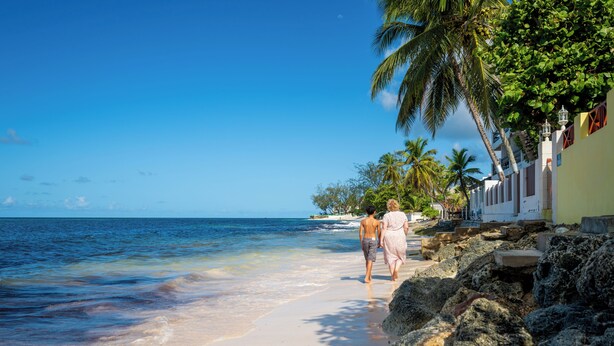 A beach with clear blue water, a sandy shore, and a few people walking along the beach. - Worthing Court Apartment Hotel (Worthing)