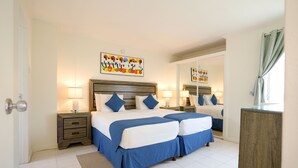 A double bed with blue bedding, a wooden headboard, bedside tables with lamps, and a large mirror. - Worthing Court Apartment Hotel (Worthing)