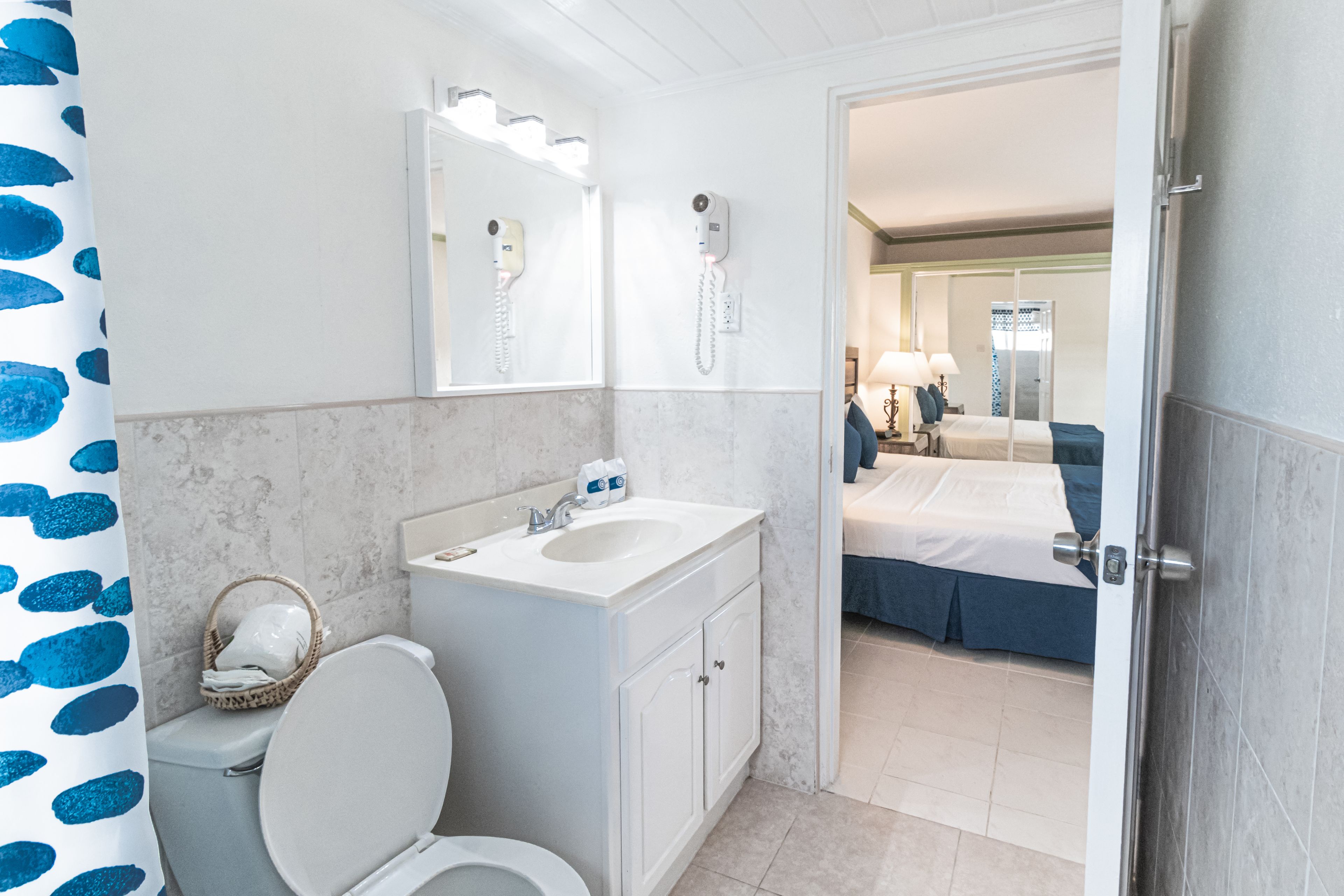 A bathroom with a toilet, sink, and two hair dryers mounted on the wall.
