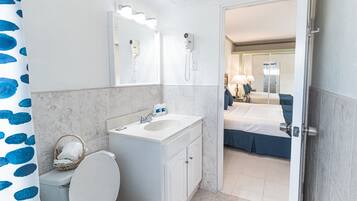 A bathroom with a toilet, sink, and two hair dryers mounted on the wall.