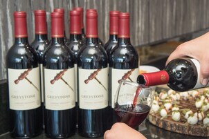 Una persona sirve vino tinto de una botella en una copa.