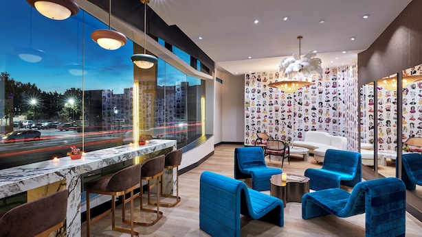 Uma área de bar moderna com bancadas de mármore, cadeiras estofadas em azul e vista para a cidade através de grandes janelas.