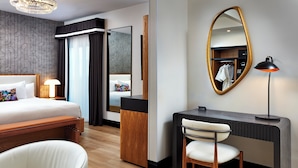 Quarto de hotel com cama, escrivaninha, cadeira e um espelho grande.