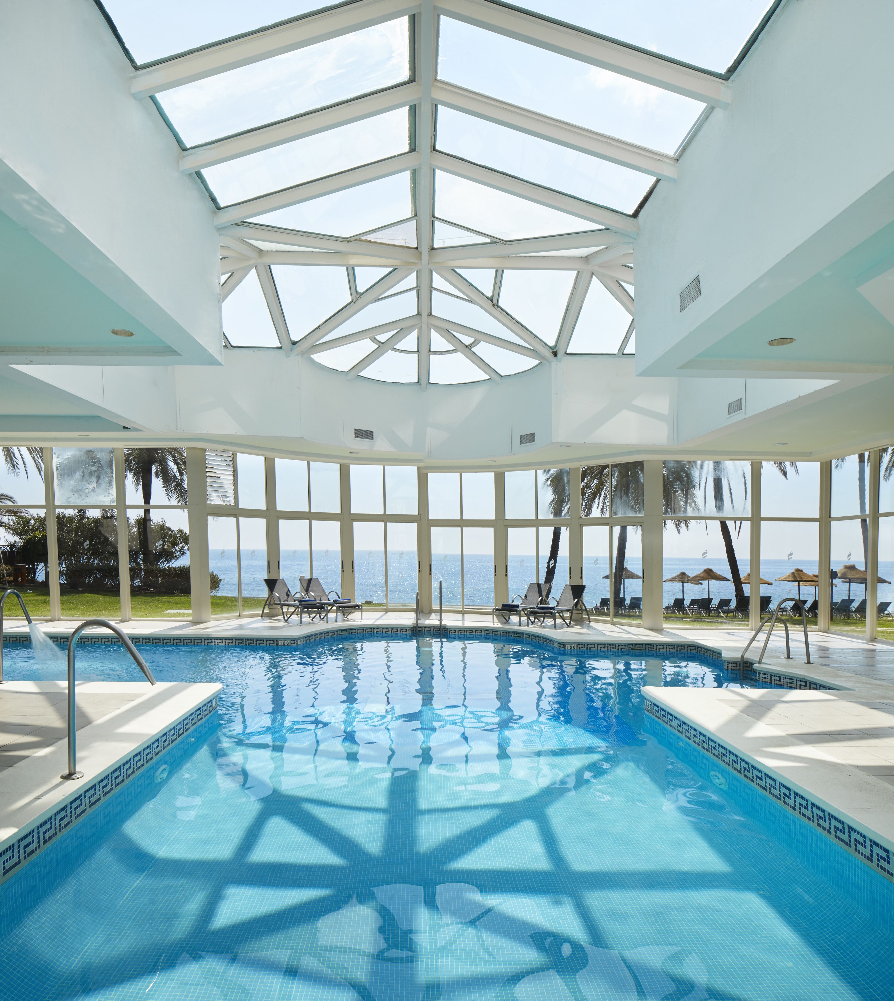 An indoor swimming pool with clear views of the ocean through large windows.
