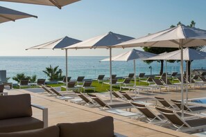 A poolside area with sun loungers and umbrellas, overlooking a body of water. - Estival Torrequebrada (Benalmádena)
