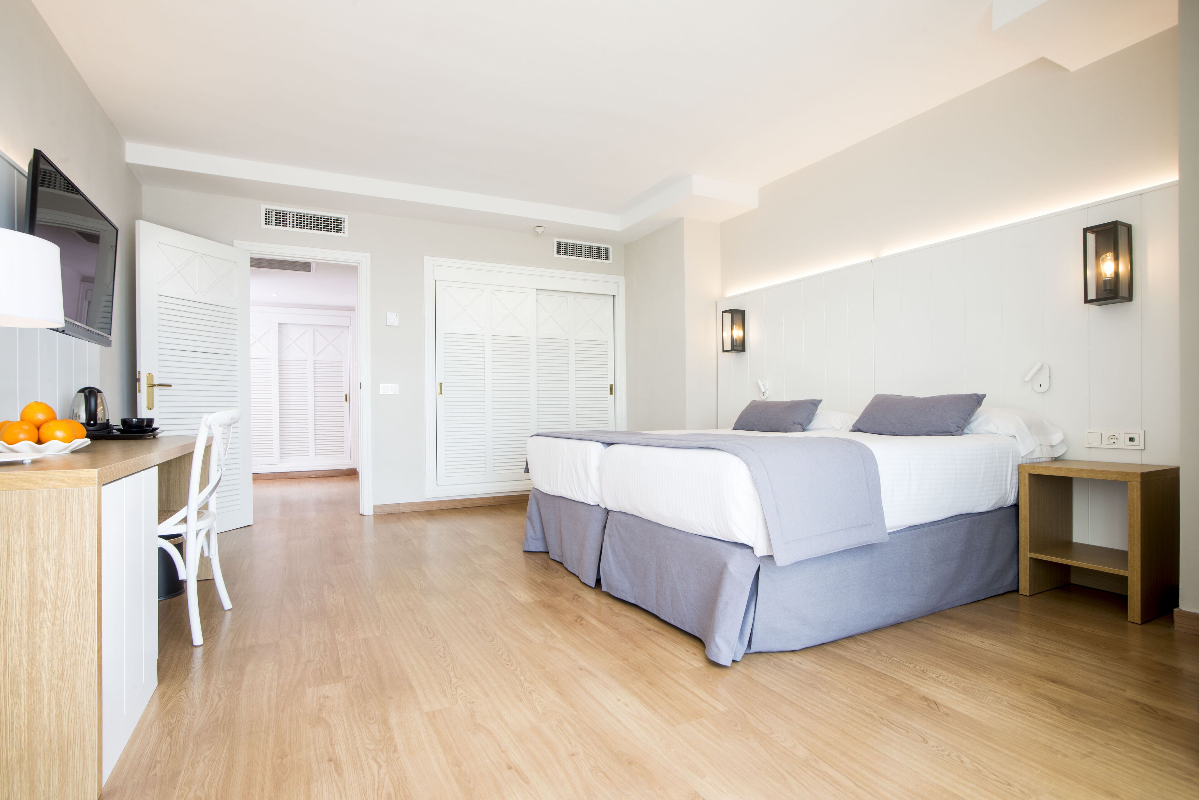 Une chambre à coucher moderne avec un lit, des tables de chevet, un bureau et une chaise.