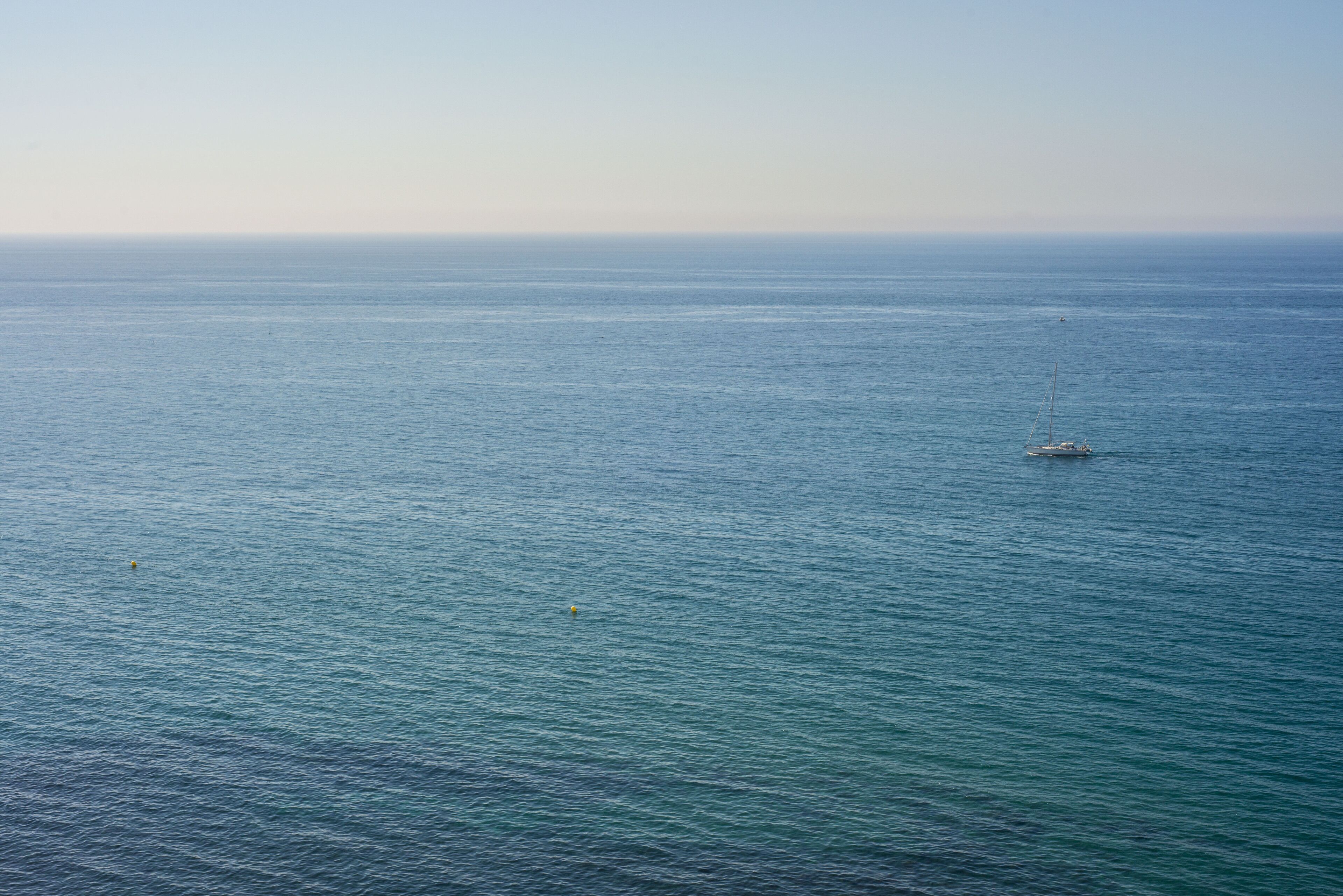 A calm sea with a sailboat in the distance.