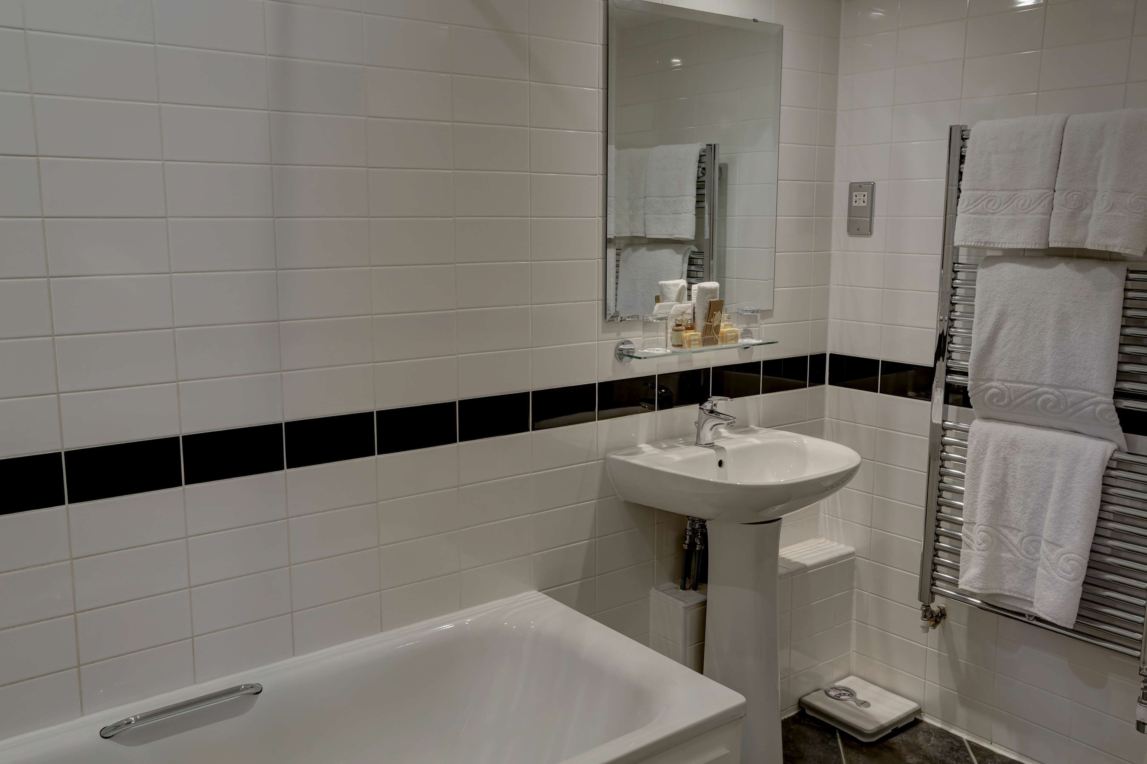 Ein modernes Badezimmer mit einem weißen Waschbecken, einem Spiegel und einer Badewanne.