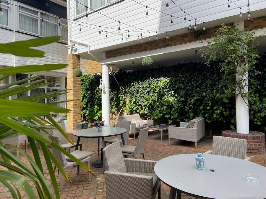 An outdoor seating area with wicker furniture, a round table, and a hanging light fixture.