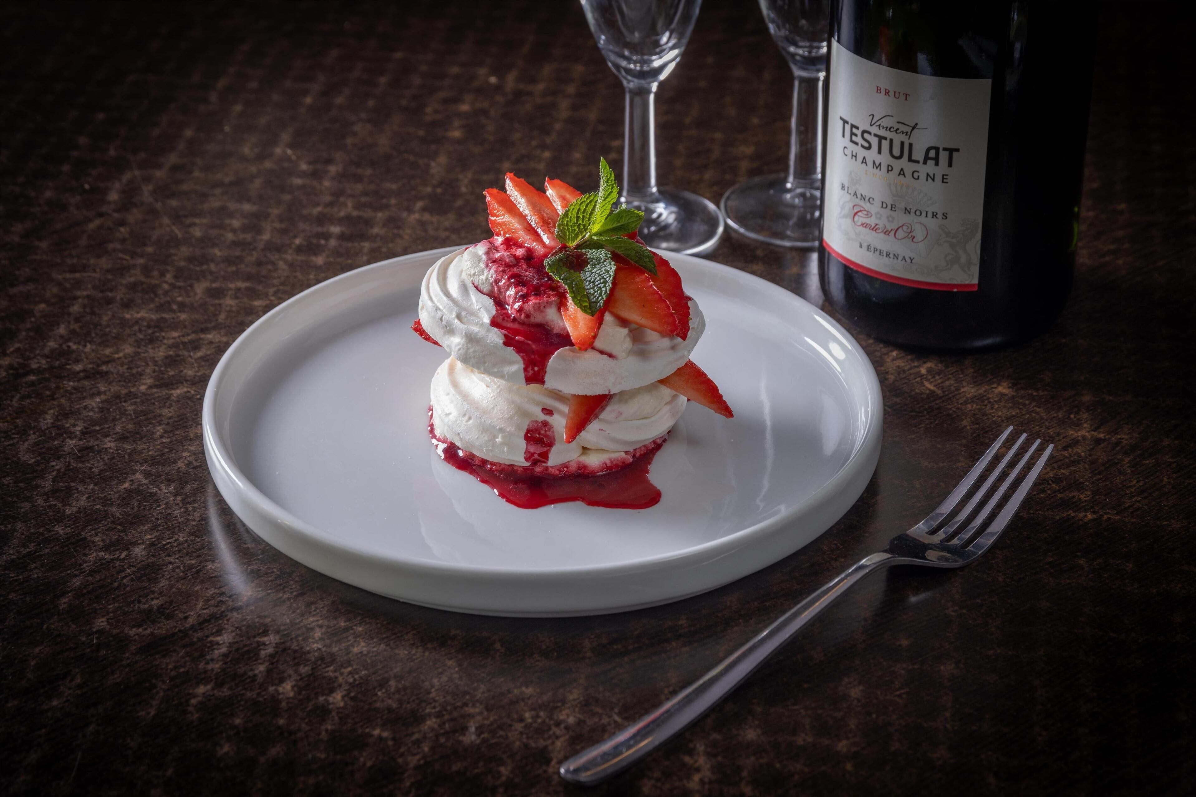 Postre a la plat amb una ampolla de Cava Brut Testulat al fons.