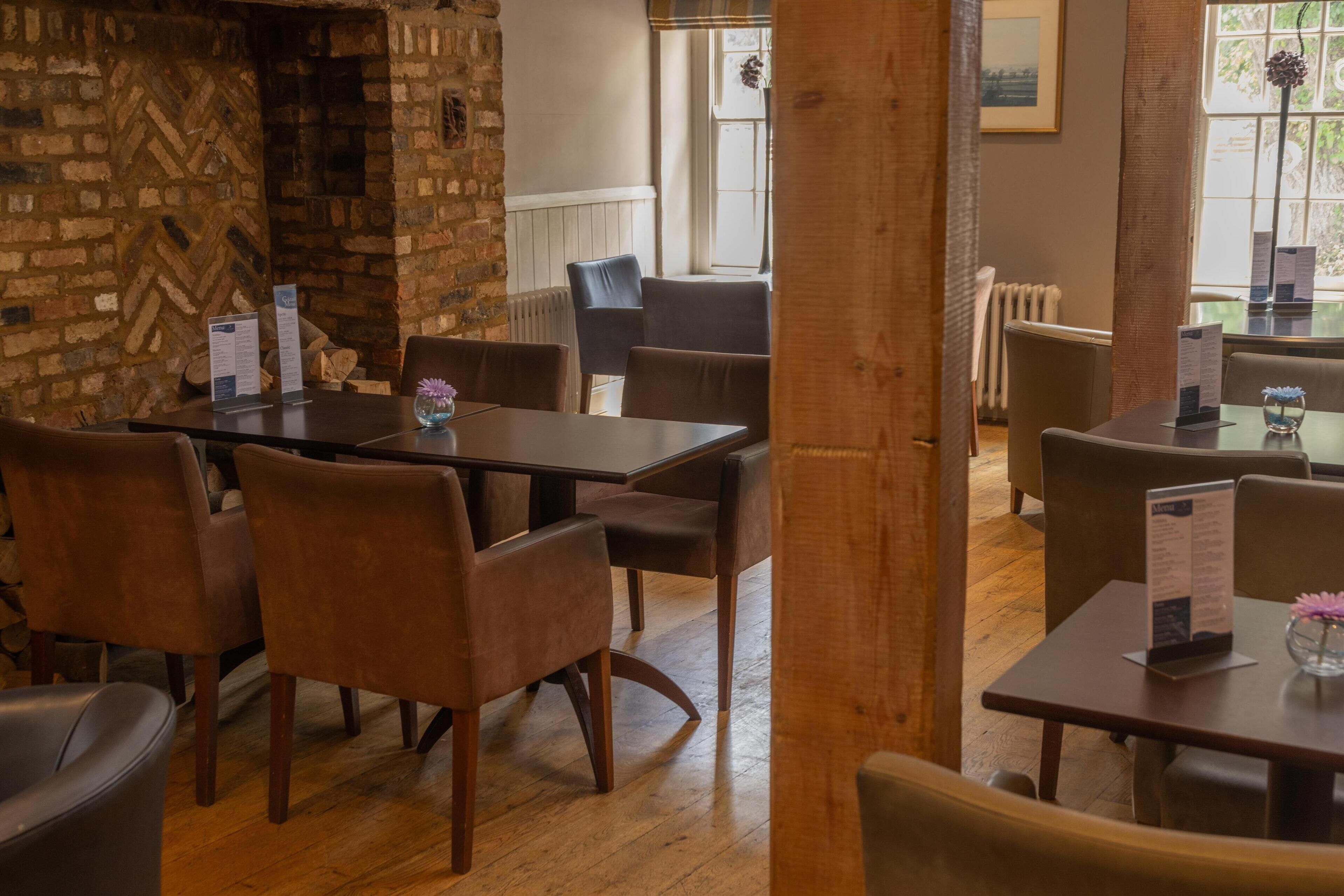 A restaurant interior with brick walls, wooden flooring, and modern furniture.