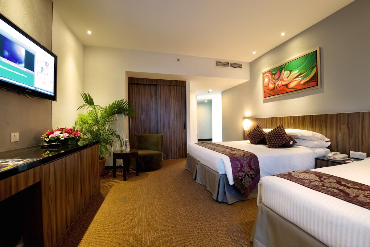 Una habitación de hotel con una cama, un escritorio con una computadora, una silla y una planta.