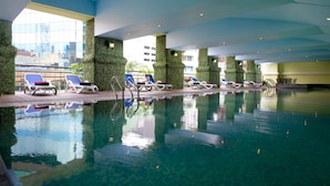 Una piscina interior con sillones de descanso y vistas a la ciudad.
