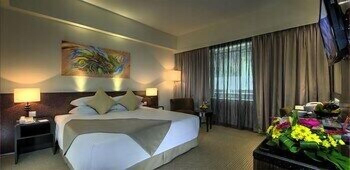 Camera d'albergo con un letto grande, due comodini, un tavolino, un quadro appeso al muro, una televisione e un bouquet di fiori.