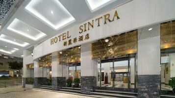 A hotel entrance with a modern design, featuring a prominent sign reading "HOTEL SINTRA" and "新加坡酒店".
