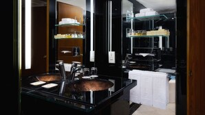A modern bathroom with a glass sink, shelves with toiletries, and a mirror reflecting the space. - Hotel Sintra (Macau)