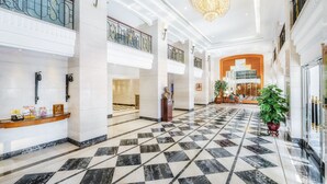 A spacious lobby with a checkered marble floor, a reception desk, and a staircase leading to an upper level. - Hotel Sintra (Macau)