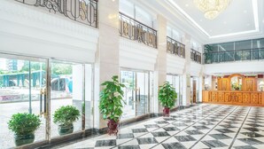 A spacious lobby with a checkered floor, large windows, and potted plants. - Hotel Sintra (Macau)