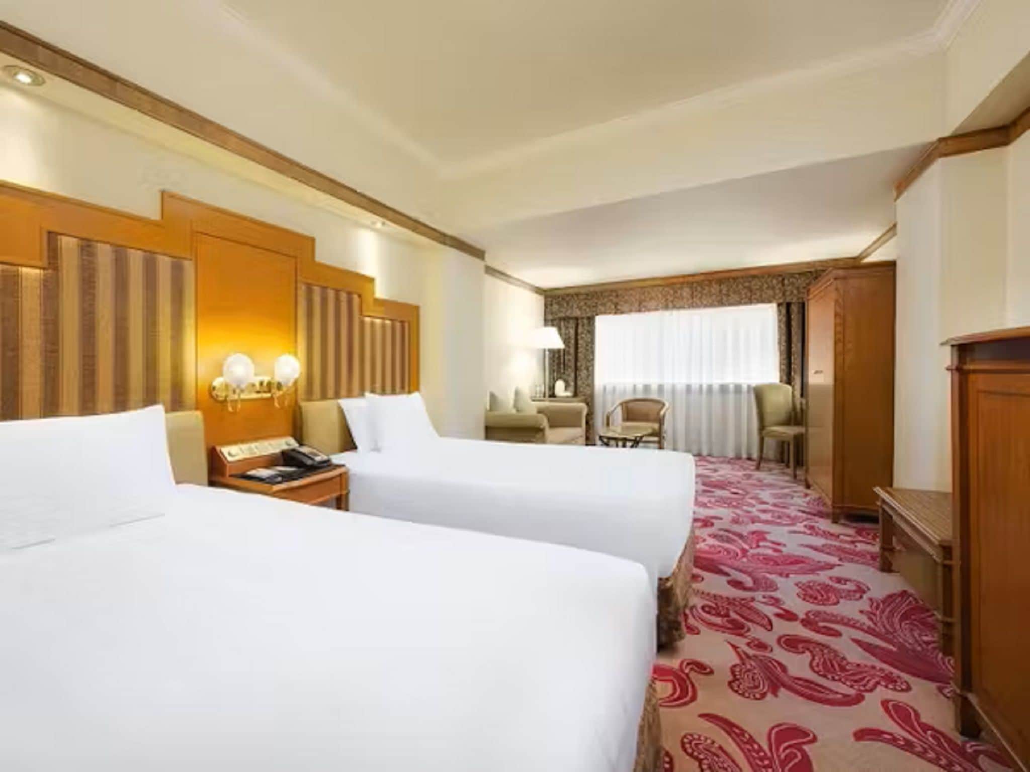 Habitación de hotel con dos camas, un escritorio, una silla y piso alfombrado.