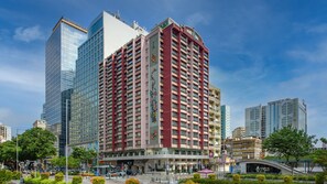 Um hotel com vários andares, fachada vermelha marcante, grandes janelas e design arquitetônico moderno.