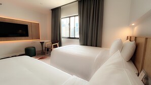 Una habitación de hotel con dos camas, televisión, una mesita y una silla.
