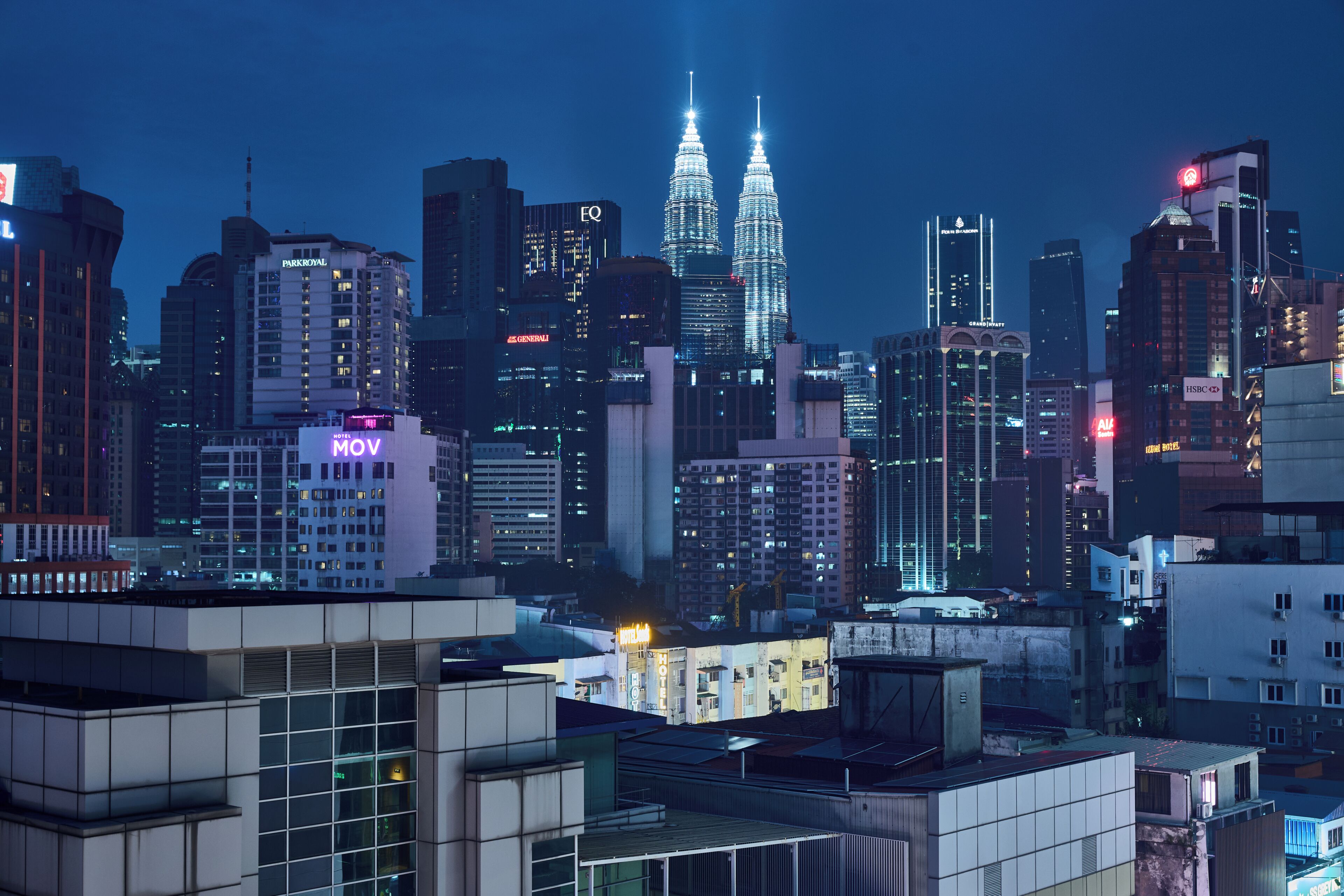 A cityscape with modern buildings, including the iconic twin towers in the center.
