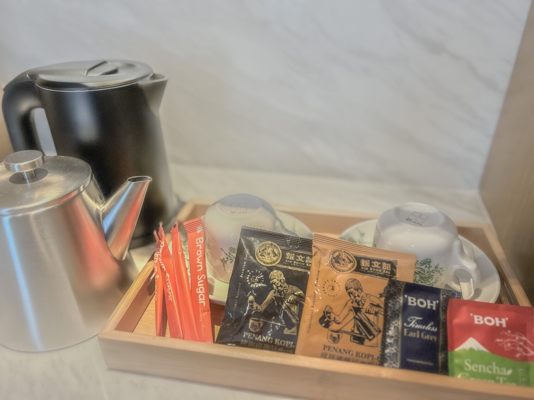 A tray with a tea set, a kettle, and several tea bags.