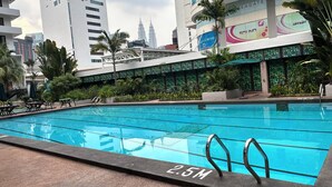 A swimming pool with a 2.5m depth marker, surrounded by greenery and modern buildings. - Federal Hotel Kuala Lumpur (Kuala Lumpur)