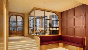 Un interior moderno con una escalera curva, un banco rojo y un gran ventanal que ofrece vistas al exterior.