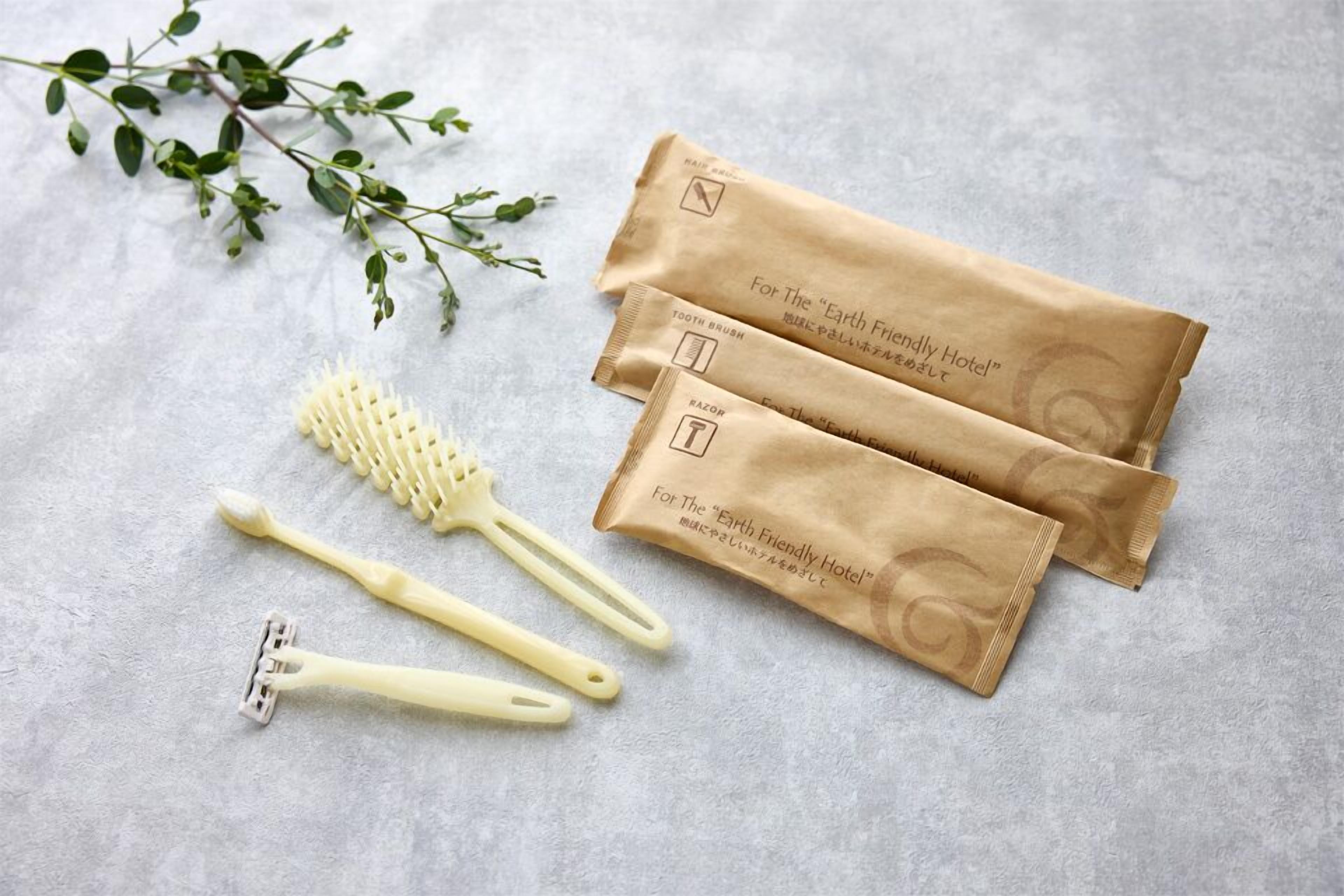 A set of grooming tools including a toothbrush, a razor, and a brush, along with two brown paper bags labeled "For The 'Earth Friendly Hotel'.