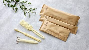 A set of grooming tools including a toothbrush, a razor, and a brush, along with two brown paper bags labeled "For The 'Earth Friendly Hotel'.