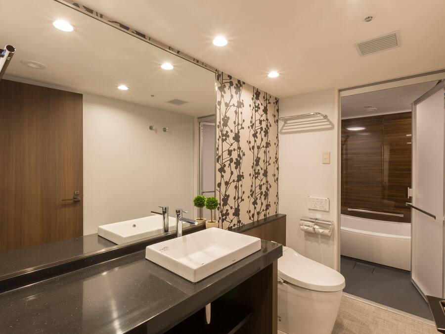 A modern bathroom with two sinks, a toilet, and a shower area.