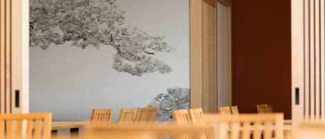Un comedor con sillas de madera y una mesa, una pared con una obra de arte en escala de grises, y una puerta de madera.