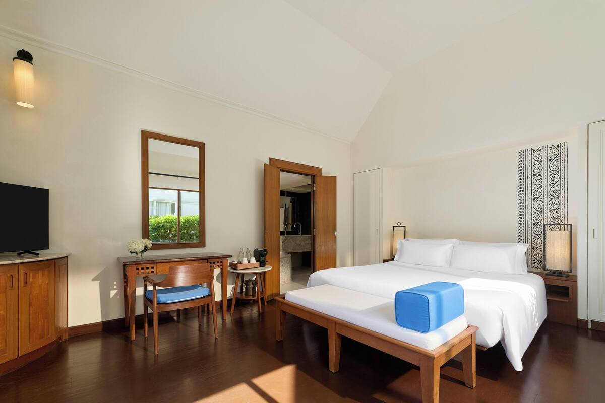A hotel room with a bed, a desk with a chair, a television, and a window with a view.