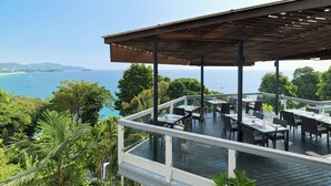 An outdoor dining area with tables and chairs, overlooking a coastal landscape. - Centara Villas Phuket (Karon)