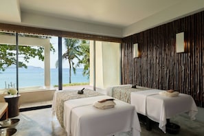 Habitación con dos camas, un ventanal con vista al mar, una bañera y una pared de madera.