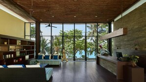 A spacious room with a high ceiling, large windows, a reception desk, and a seating area with cushions. - Centara Villas Phuket (Karon)