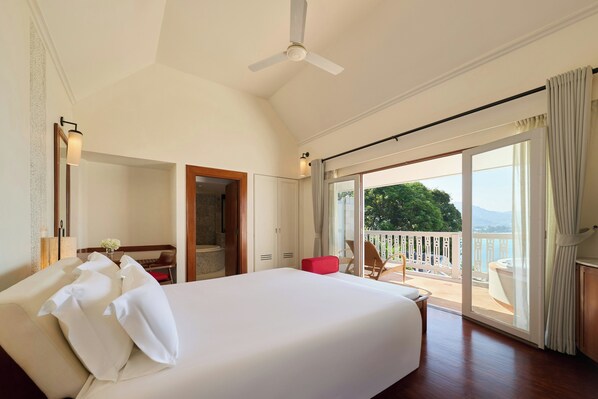 A hotel room with a large bed, a ceiling fan, a balcony with a view, and a sliding glass door. - Centara Villas Phuket (Karon)