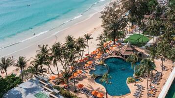 Un resort con piscina, playa y palmeras.