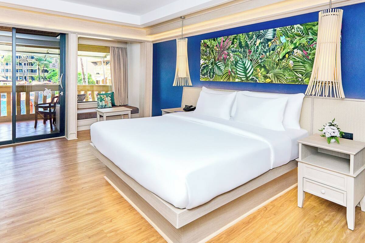 Une chambre d’hôtel spacieuse, dotée d’un grand lit, d’un bureau et offrant une vue sur l’extérieur.