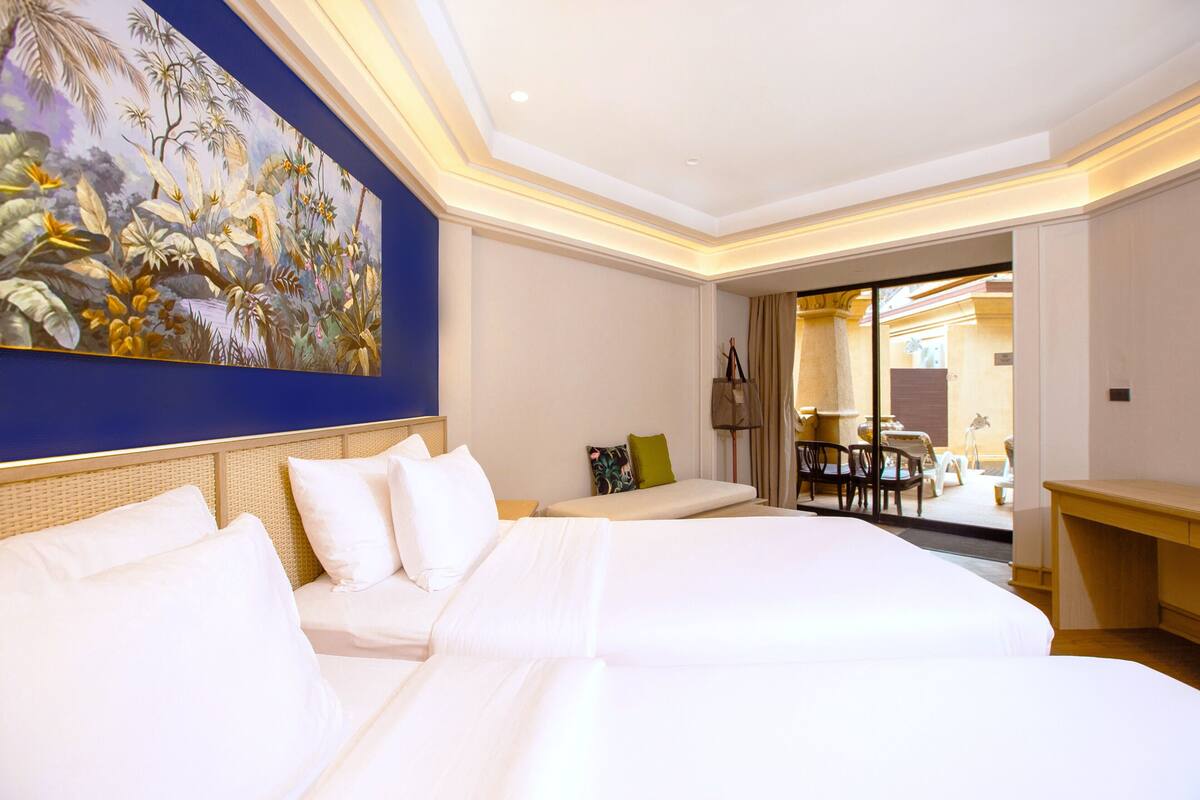 Une chambre d’hôtel avec un grand lit, un bureau, une chaise et un coin repas comprenant une table et des chaises.