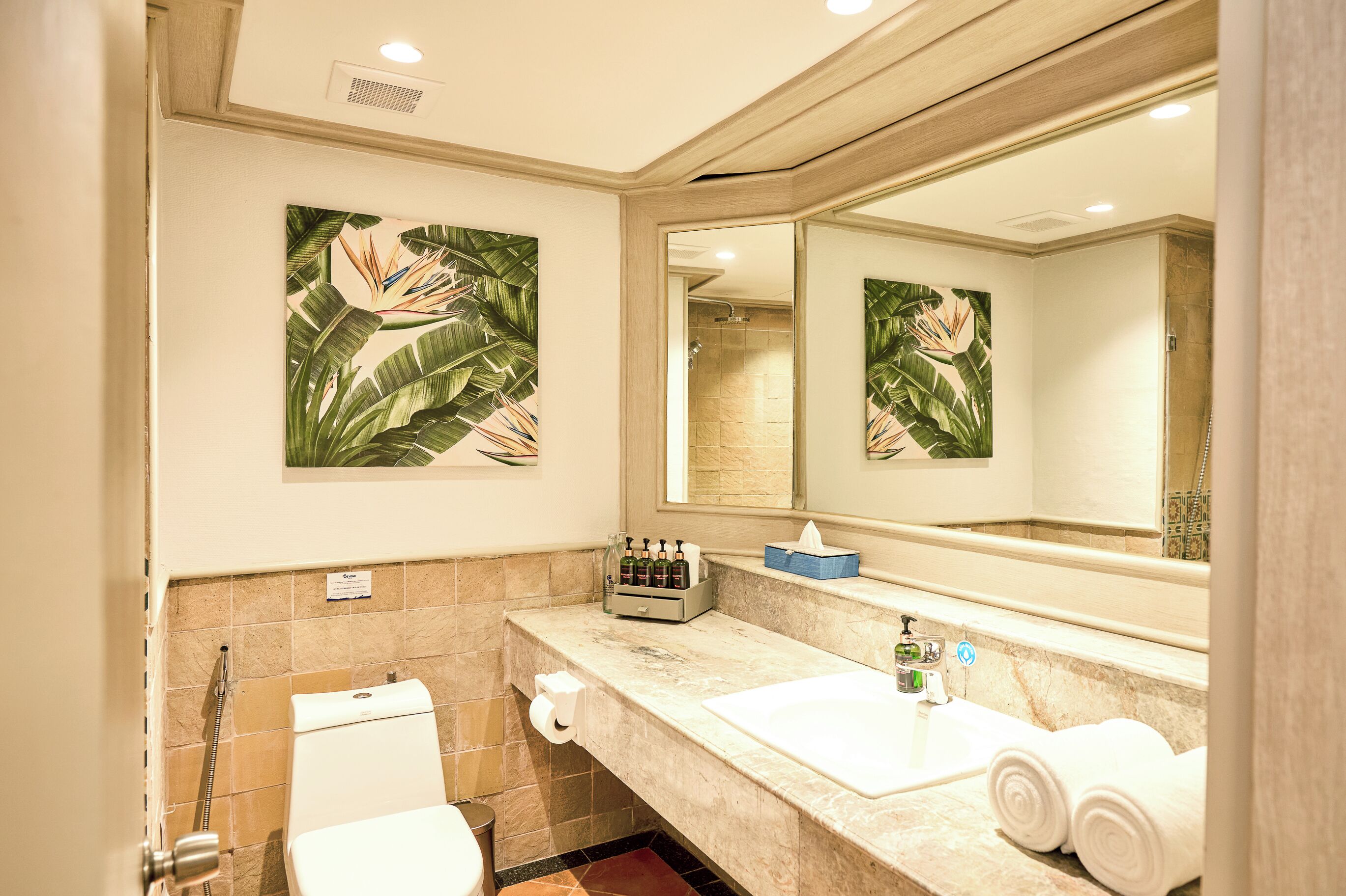 A bathroom with a toilet, sink, and shower. There are towels and toiletries on the sink counter.