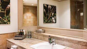 A bathroom with a marble sink, a large mirror, and two floral wall art pieces.