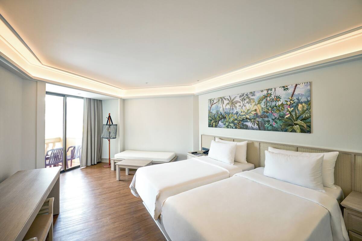 Une chambre d’hôtel avec deux lits, un bureau et une grande fenêtre.