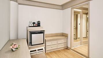 Una habitación de hotel compacta con kitchenette, un pequeño rincón de descanso y una puerta que da a un pasillo.